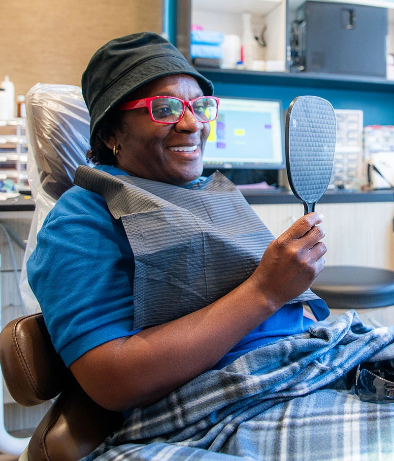 A patient looking into a mirror while sitting in the exam chair at 10 Day Smiles in Arlington TX.